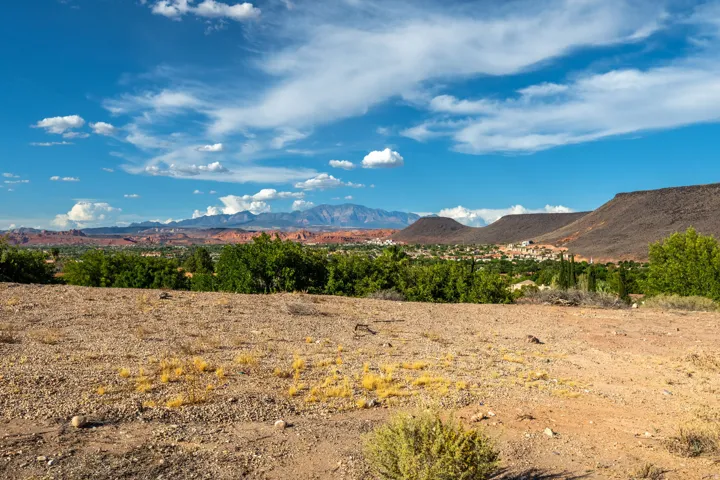 Expansive desert landscape featuring distant red rock formations and a community of structures