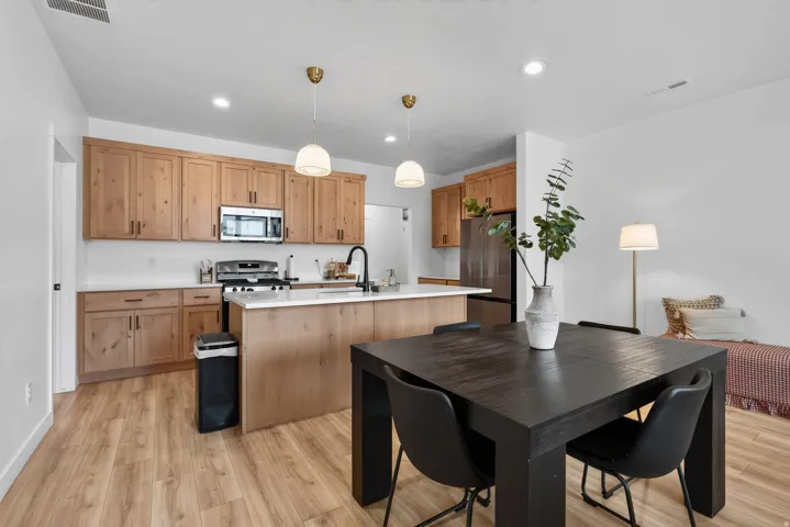 Main floor kitchen featuring wood cabinetry, stainless steel appliances, white countertops, and wood-finish flooring.