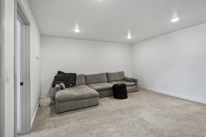 Upper level loft space with recessed ceiling lighting illuminates a spacious room featuring light-colored wall-to-wall carpeting and bright white walls