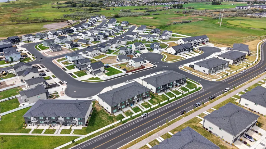 Newly developed residential community with a mix of single-family homes and townhomes, featuring paved streets and manicured landscaping.