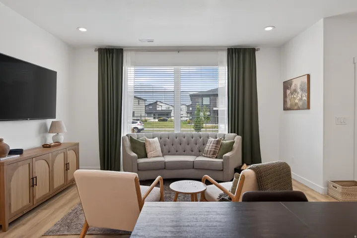 Main floor living room with recessed lighting illuminates the interior, featuring wood-finish flooring and a large window with blinds.