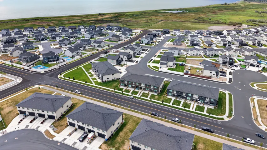 Residential development featuring a variety of single-family homes and townhomes, paved streets, and green spaces.