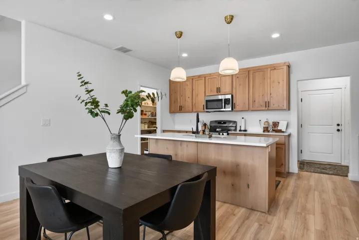 Main floor kitchen with wood-finish flooring throughout, kitchen with wood cabinetry, stainless steel appliances, and a central island with a white countertop.