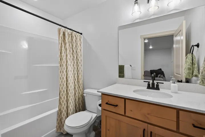 Second floor main hall bathroom with white bathtub and shower combination, wood-finish vanity with countertop, undermount sink, and black fixtures.