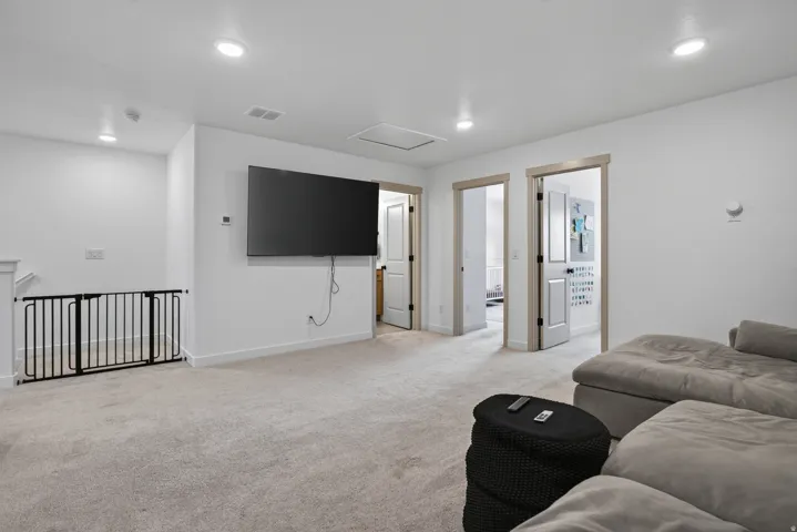 Upper level loft space featuring recessed lighting, light-toned carpet flooring, and multiple doorways with light wood trim.