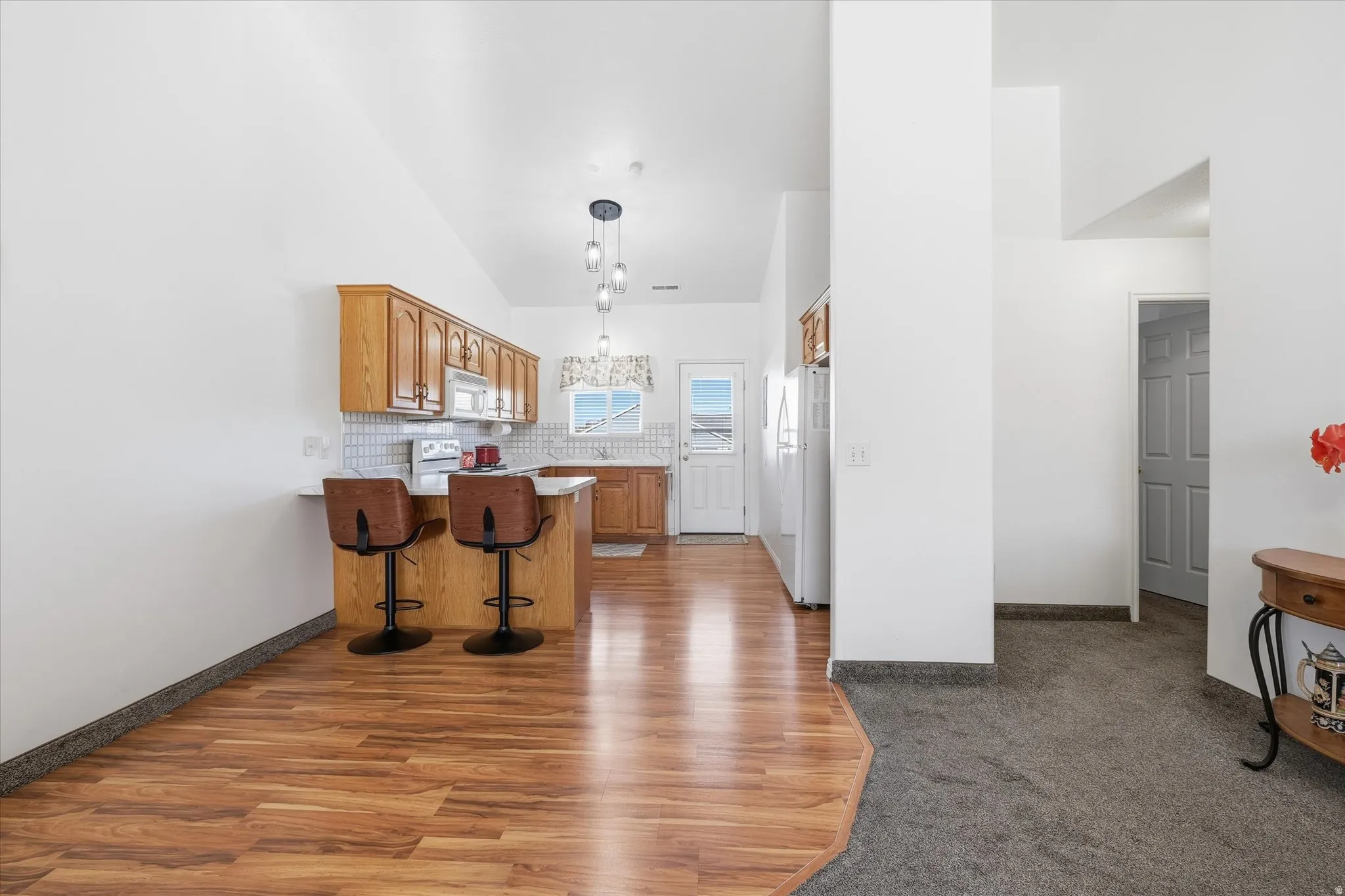 Kitchen featuring wood-finish cabinetry, white appliances, and a tile backsplash