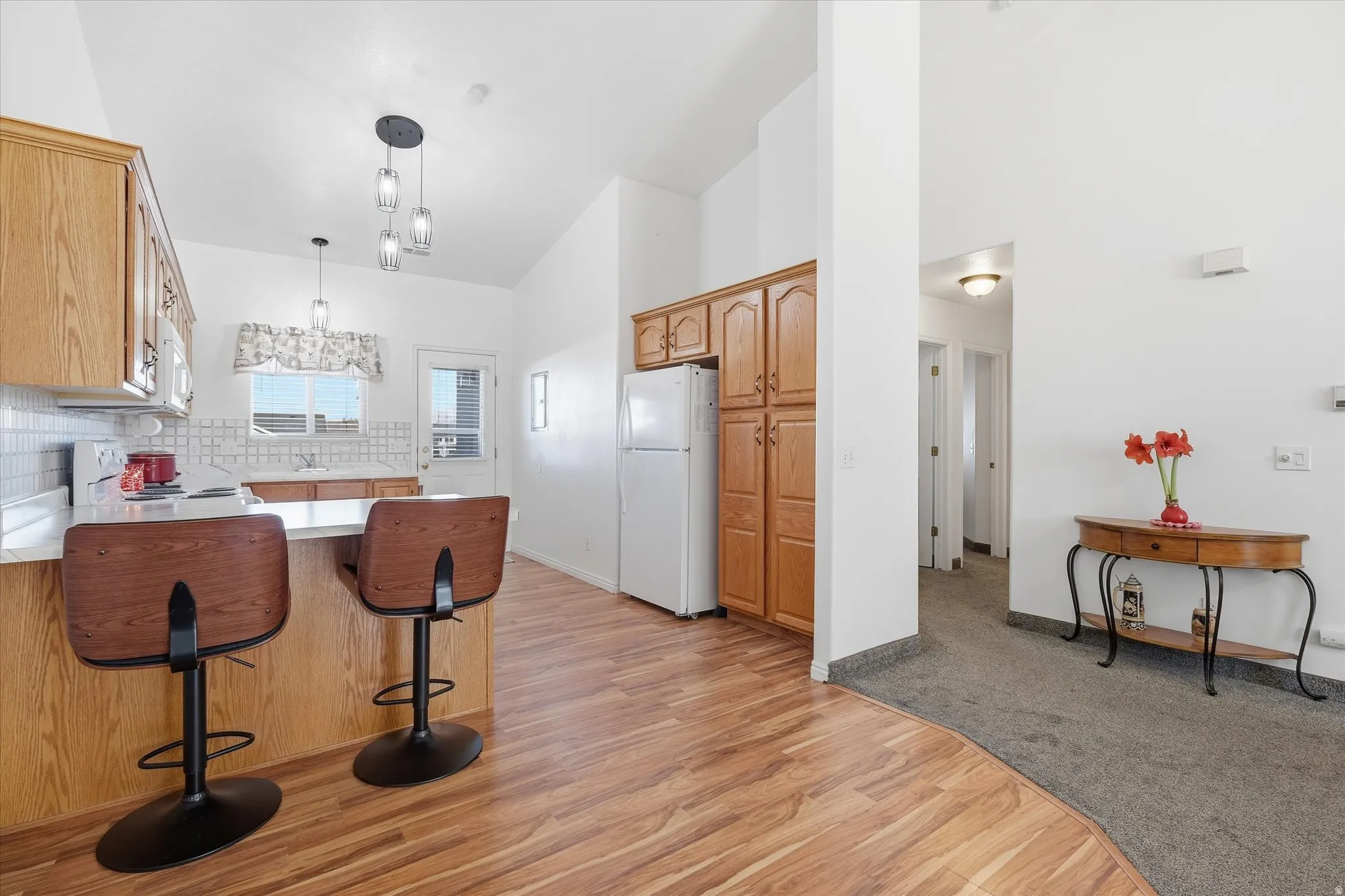 Kitchen featuring wood-finish cabinetry, white countertops, tile backsplash, and wood-finish flooring