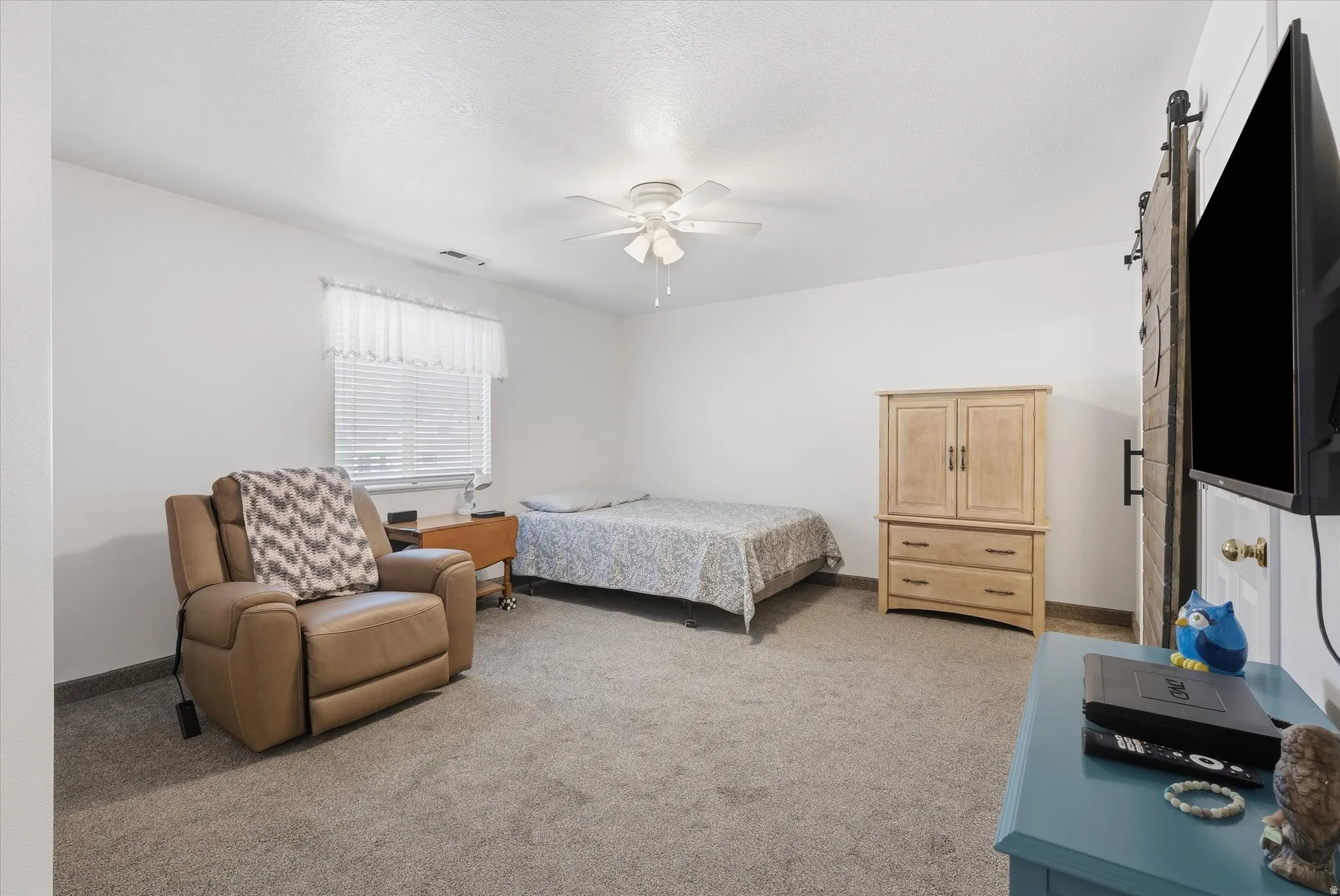 Wall-to-wall carpeting and white painted walls with a ceiling fan light fixture