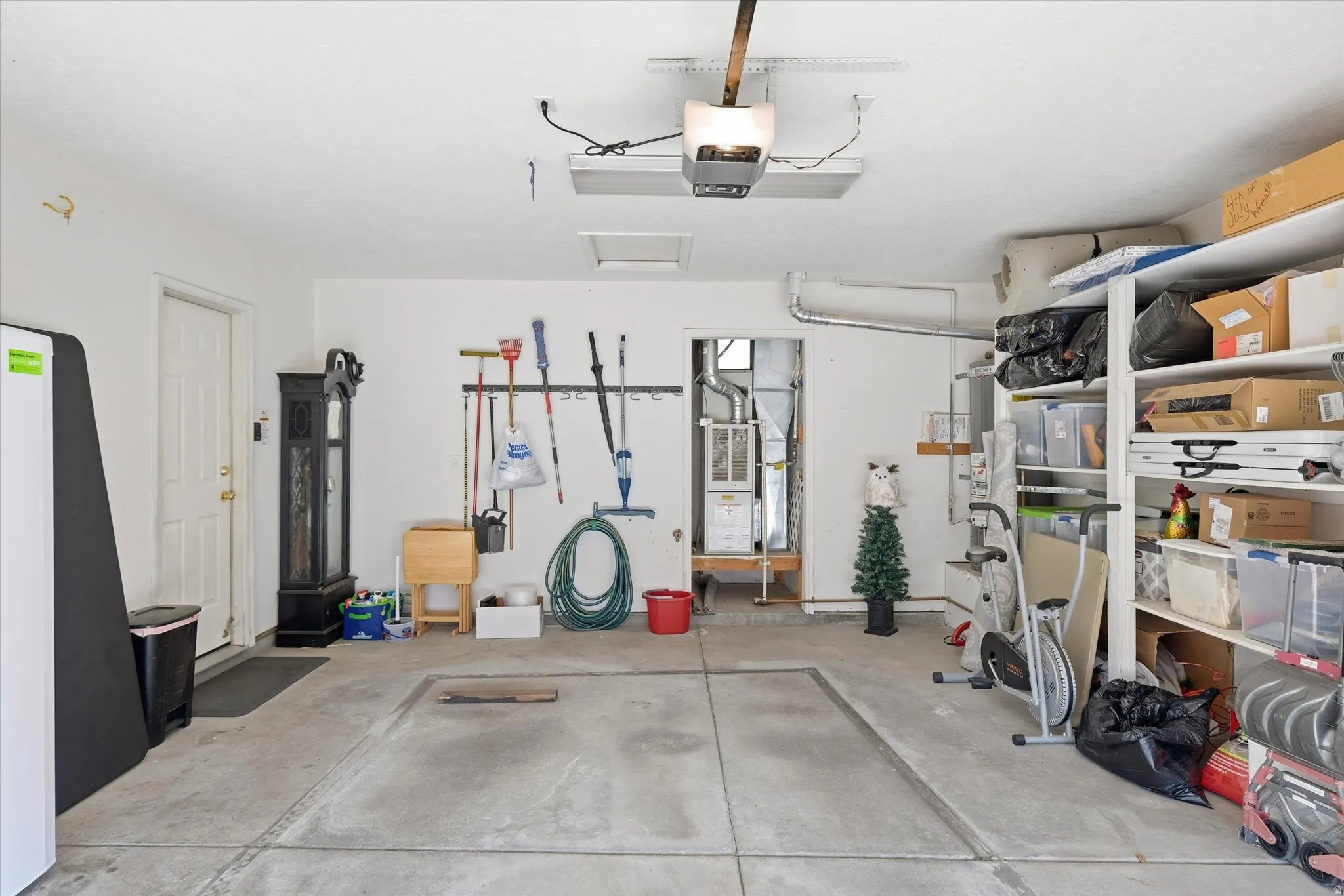 Concrete flooring, overhead garage door opener, built-in shelving, white paneled door