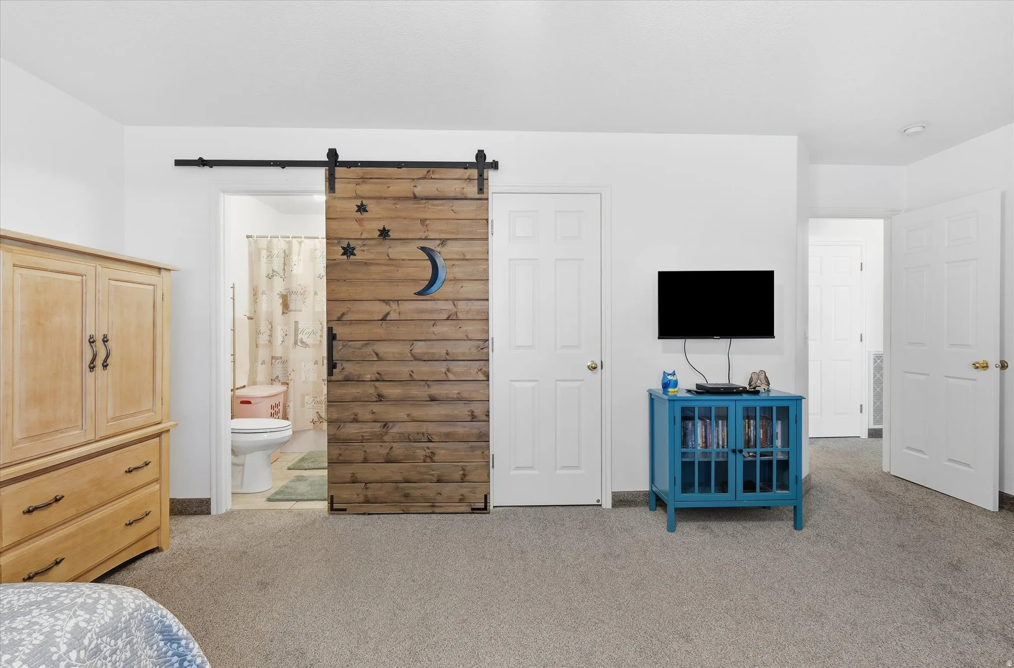 Wood-finish barn door entry to bathroom with toilet and shower