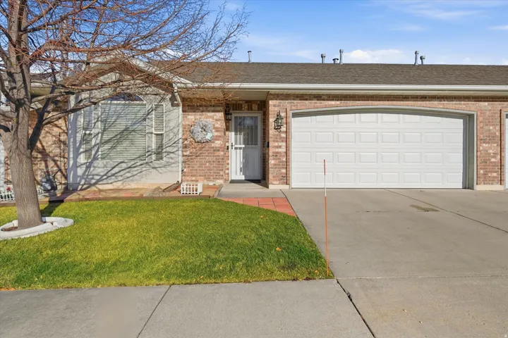Brick exterior with a prominent arched garage door, concrete driveway, and a front entry with an exterior light fixture