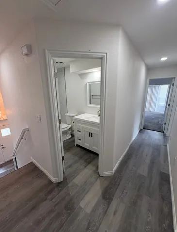 Contemporary bathroom featuring a white vanity with dark hardware, a rectangular mirror, and a toilet
