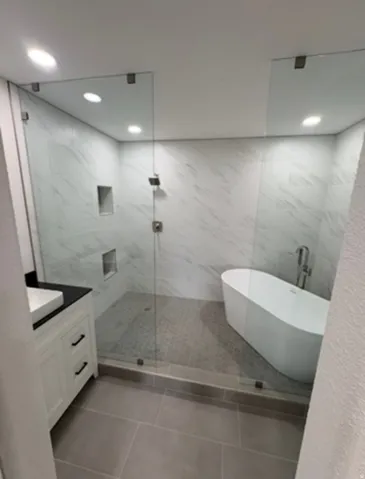 Spacious walk-in shower with floor-to-ceiling tile, dual shower niches, and a freestanding tub