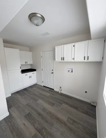 White cabinetry with matte black hardware, dark countertop, wood-finish flooring, and a flush-mount ceiling light
