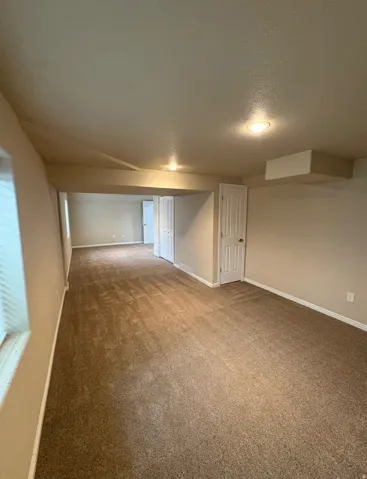 Expansive carpeted area with recessed lighting and a neutral wall palette