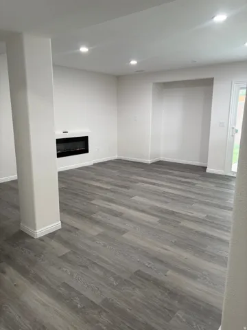 Wood-finish flooring, built-in electric fireplace, recessed ceiling lighting, and patio door