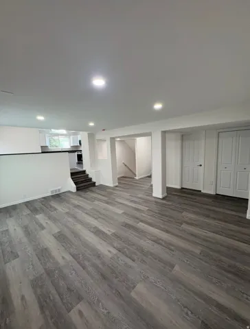 Spacious open-concept room with wood-finish flooring, recessed lighting, and white paneled interior doors