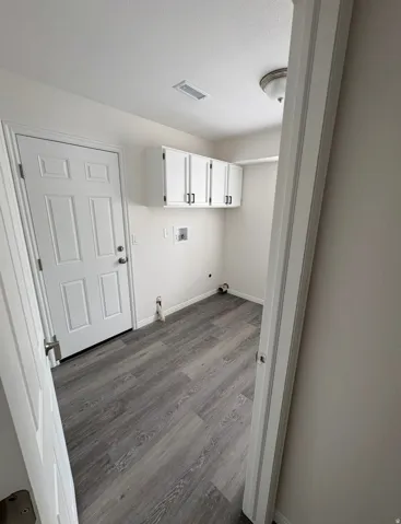 Wood-finish flooring, white cabinetry with black hardware, and a ceiling-mounted light fixture