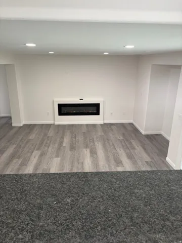 Spacious interior with wood-finish flooring, recessed lighting, and a built-in electric fireplace