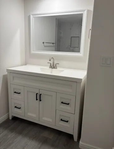 White vanity with shaker-style cabinetry, matte black hardware, integrated sink, and brushed nickel faucet