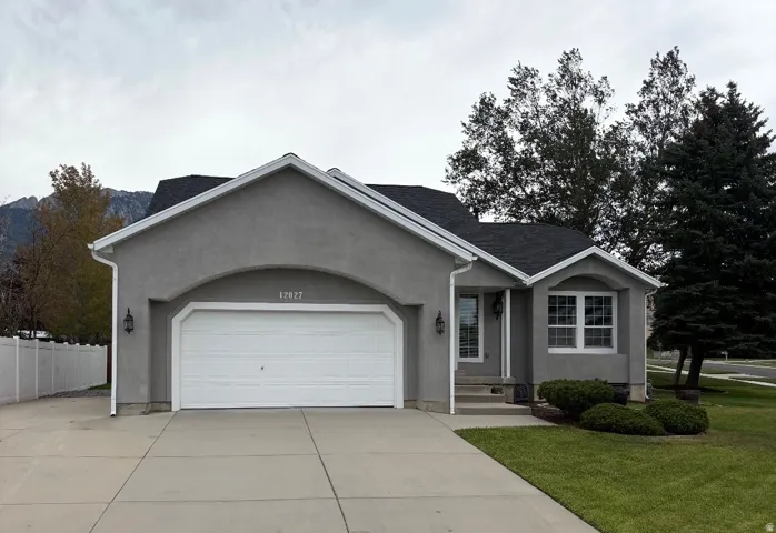 Stucco exterior with a two-car garage, concrete driveway, and front lawn landscaping