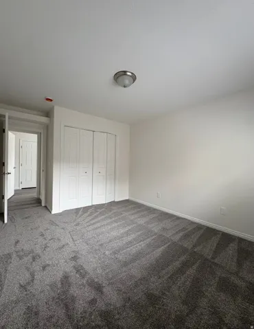 Neutral wall color with plush gray carpeting and white bi-fold closet doors