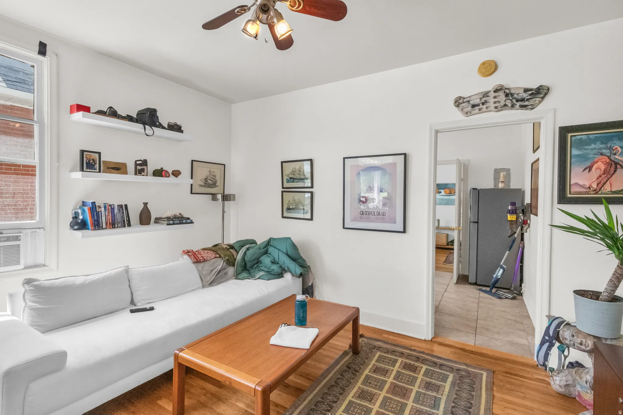 Wood-finish flooring, white walls, and a ceiling fan with integrated lighting