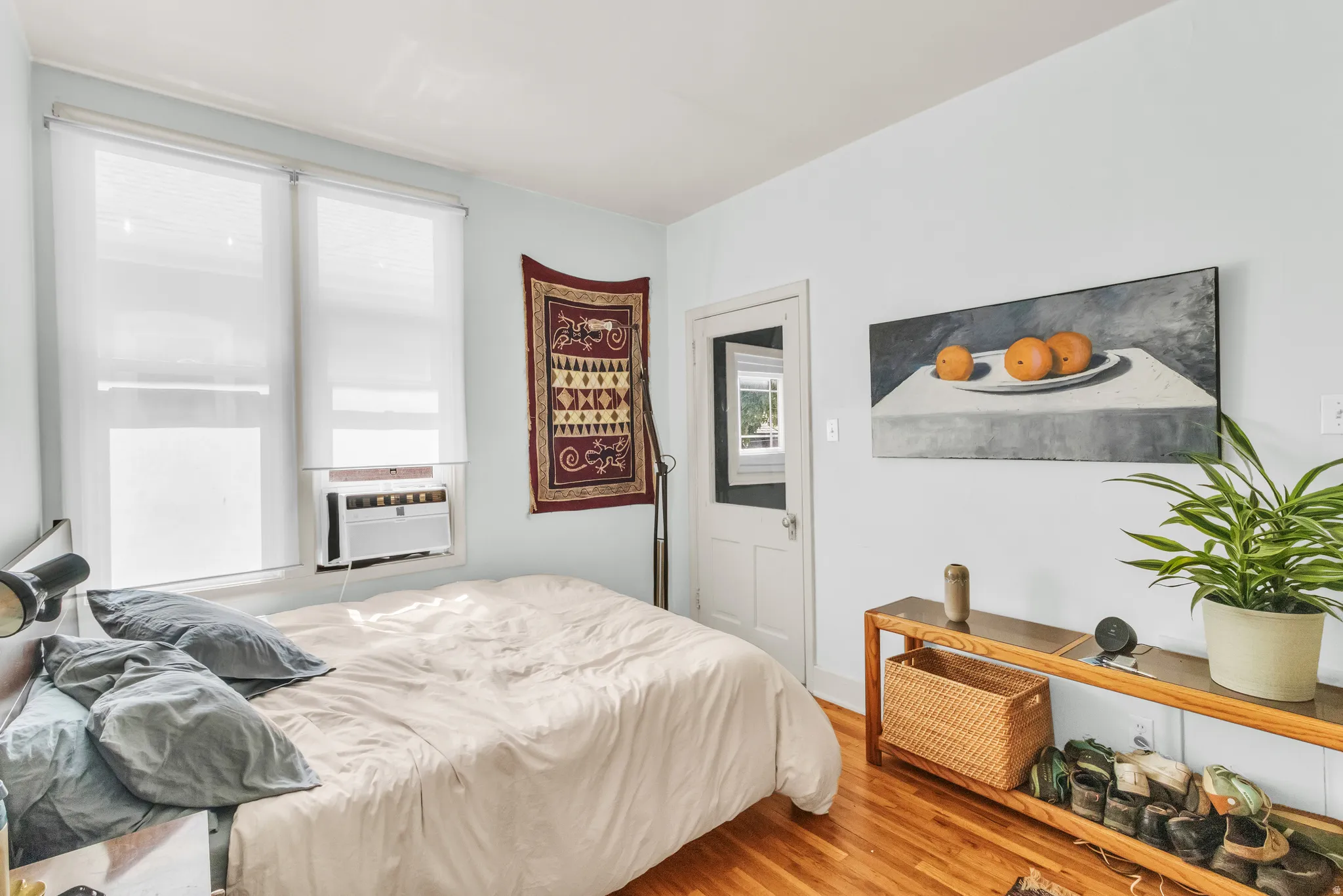 Wood-finish flooring with white baseboards, light blue wall paint, and white trim around windows and doorway
