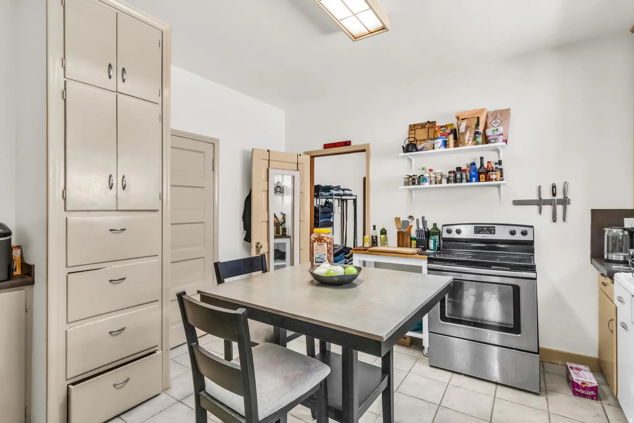 Kitchen featuring floor-to-ceiling cabinetry, white tile flooring, a stainless steel range, and open shelving