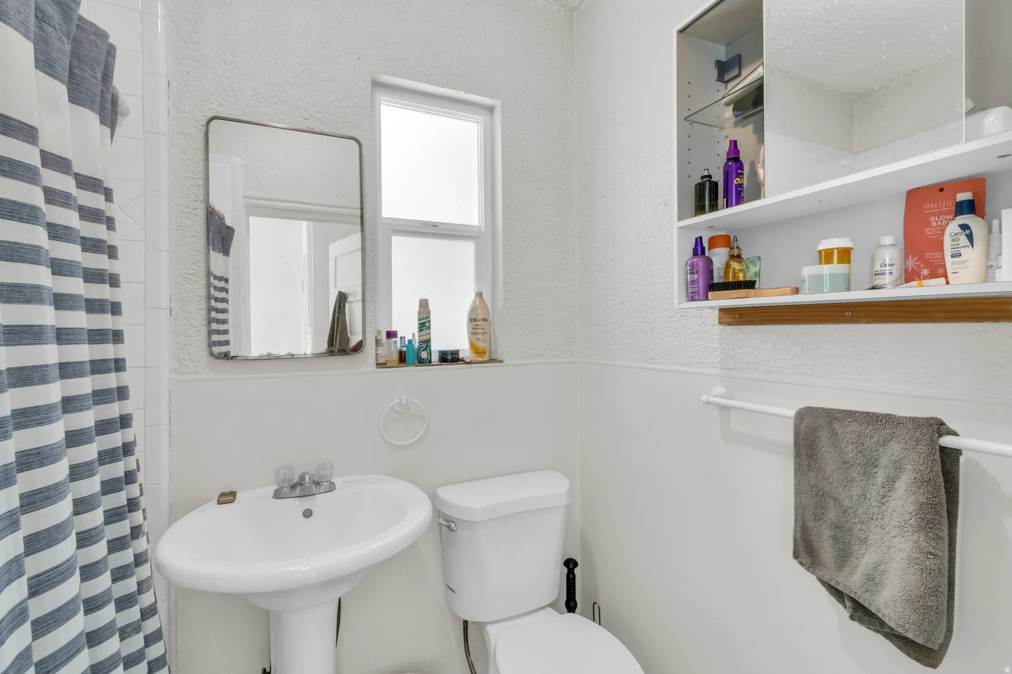 Pedestal sink with chrome fixtures, window with privacy glass, wall-mounted medicine cabinet, and towel bar