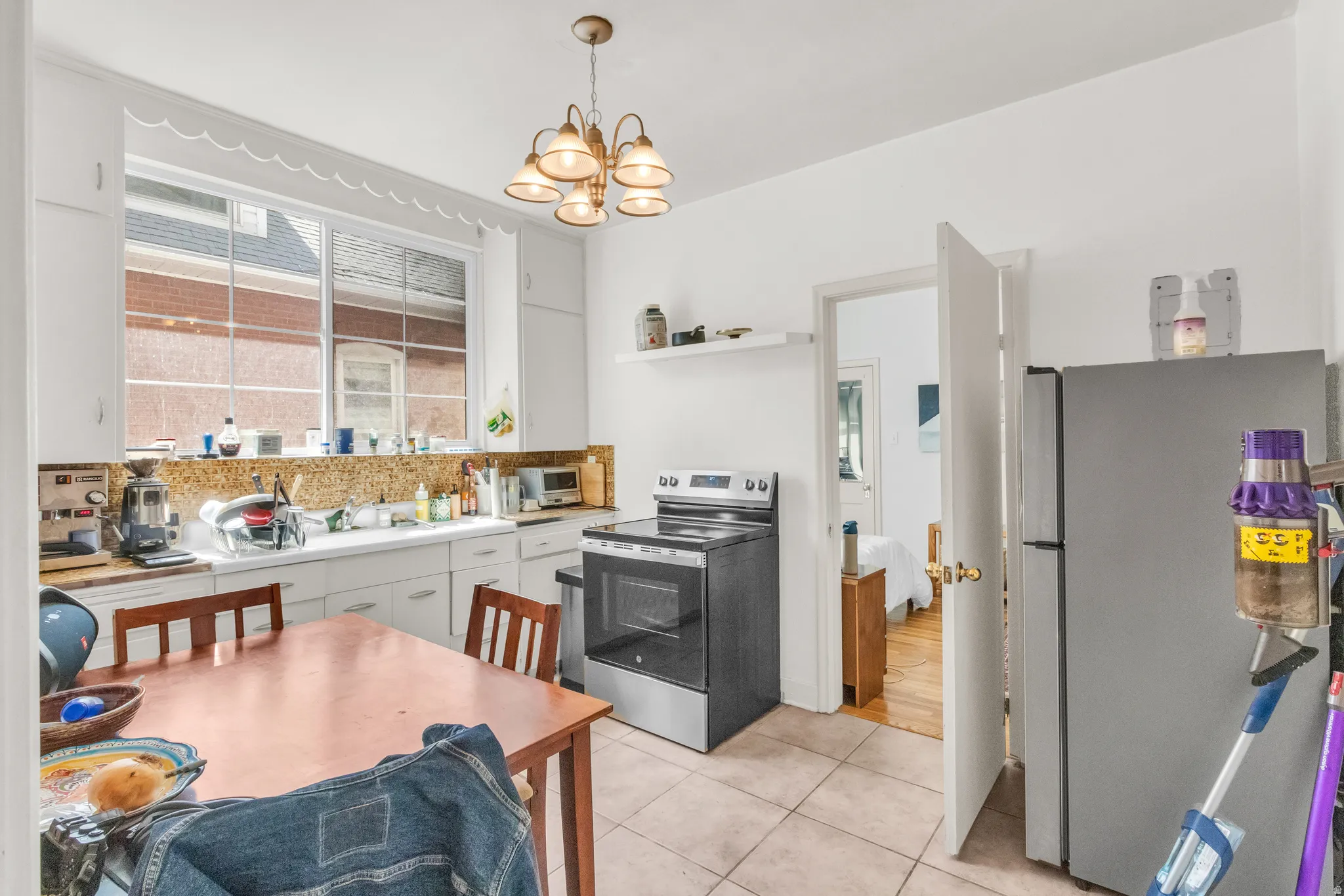 Kitchen featuring white cabinetry, large window, tile flooring, and a stainless-steel range