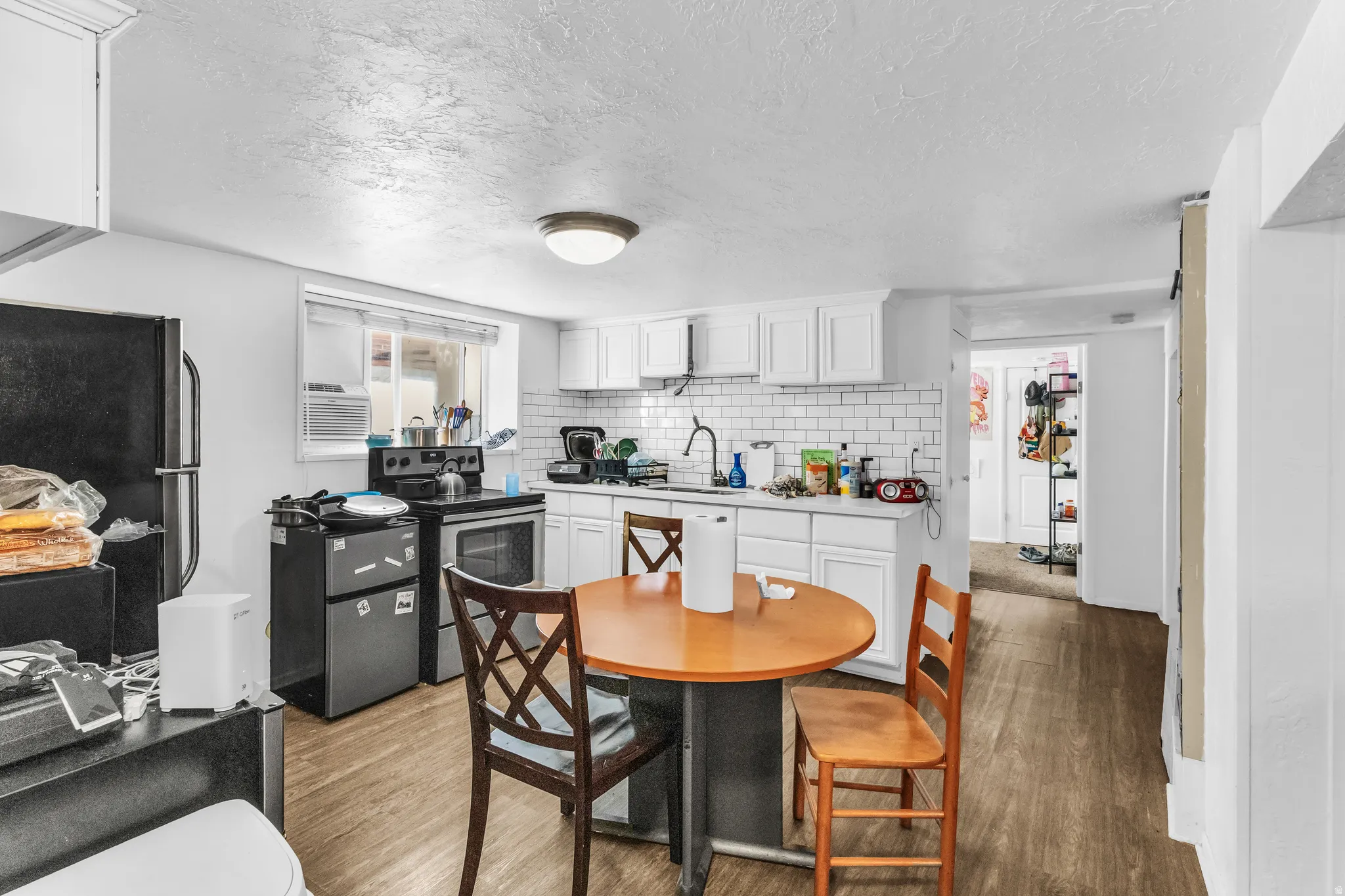 Kitchen featuring white cabinetry, subway tile backsplash, a window, dark wood-finish flooring, and a ceiling-mounted light fixture