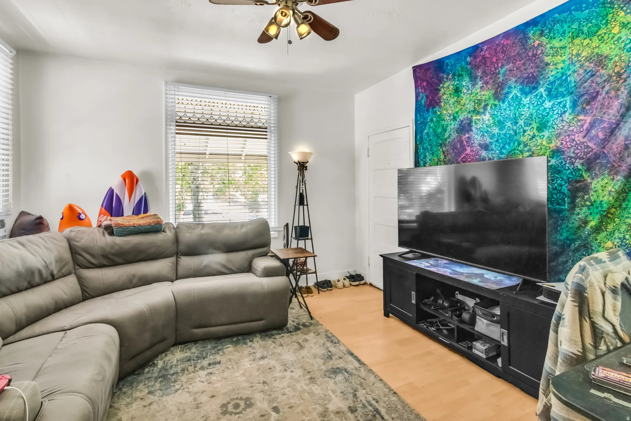 Wood-finish flooring with white walls, white window blinds, and a ceiling fan