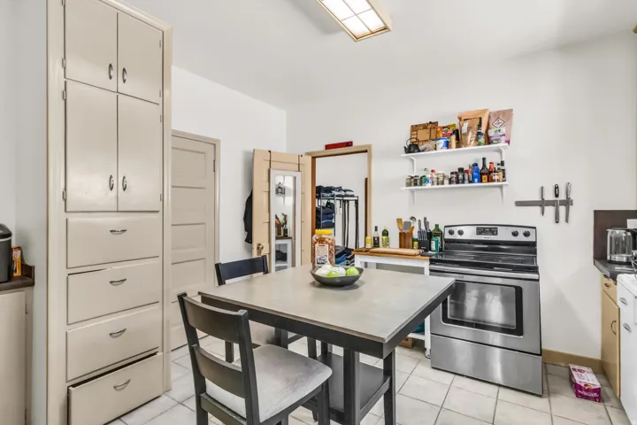 Kitchen featuring floor-to-ceiling cabinetry, white tile flooring, a stainless steel range, and open shelving