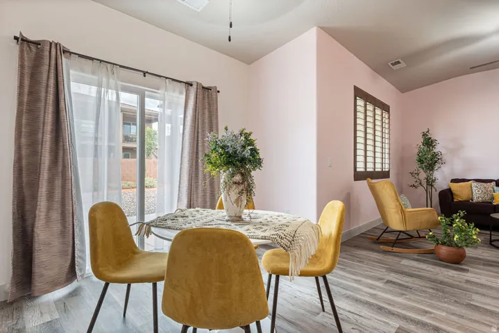 Sliding glass door access to the exterior, wood-finish flooring, and a window with plantation shutters