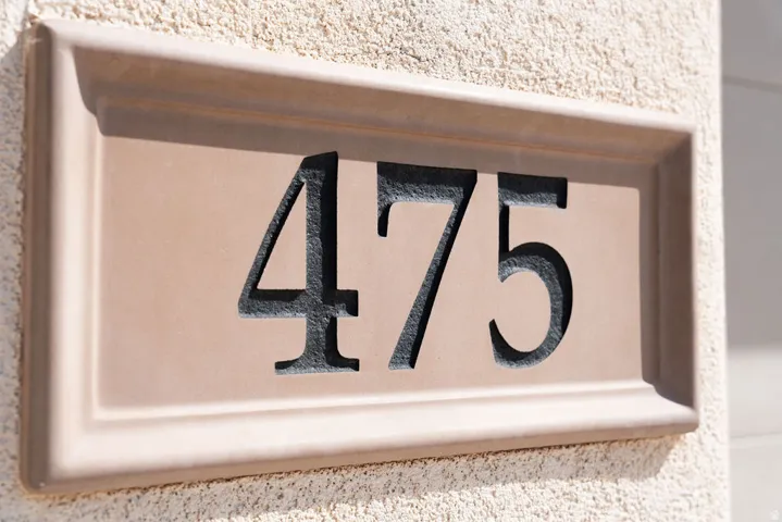 Stucco exterior with a decorative address plaque featuring carved numerals