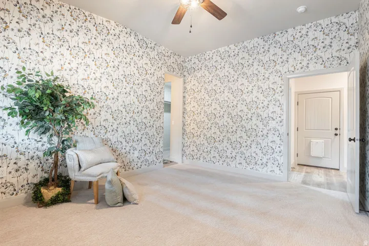 Textured wallpaper with a botanical pattern, light-toned carpeting, recessed lighting, and a ceiling fan with a wood-finish