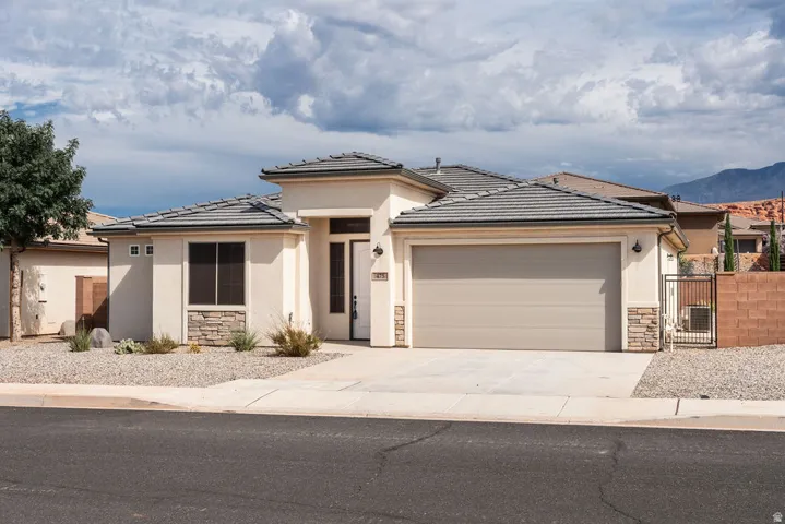 Contemporary stucco exterior with stone accents, a two-car garage, and a tile roof