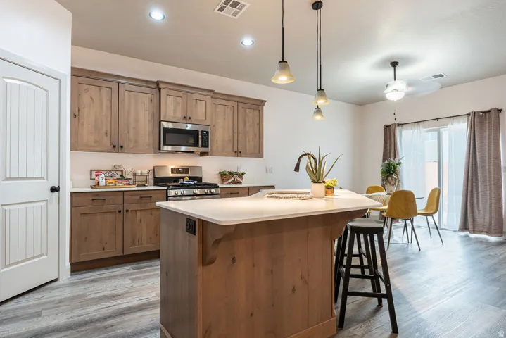 Kitchen featuring wood-finish cabinetry, stainless steel appliances, a center island with countertop seating, and recessed lighting