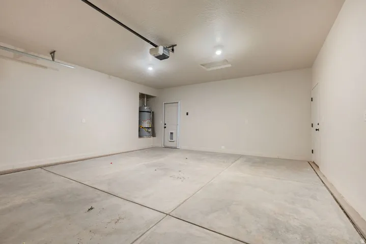 Attached garage with concrete flooring, recessed lighting, and a utility alcove