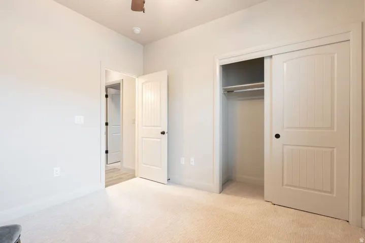 Neutral tone wall paint, carpet flooring, ceiling fan, bi-fold closet doors, and interior paneled doors