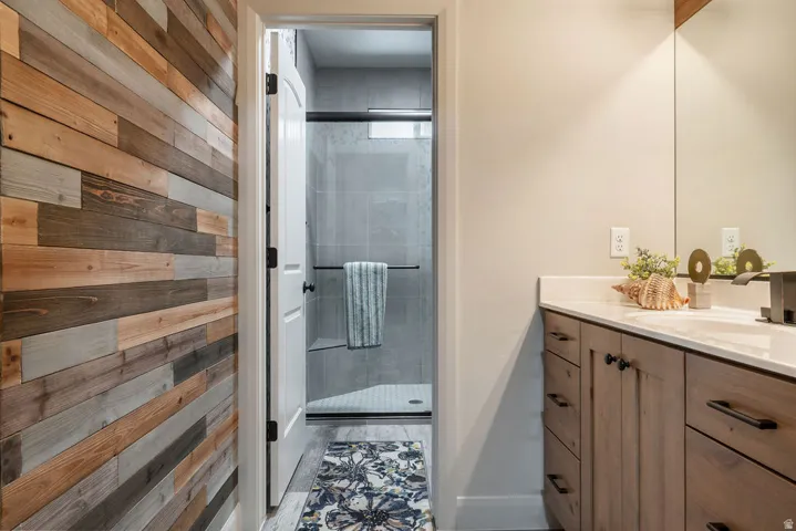 Wood-panel accent wall, wood-finish vanity with dark hardware, integrated sink, and a framed mirror