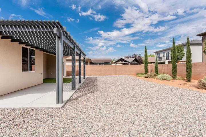 Stucco exterior with a covered patio and a slatted pergola