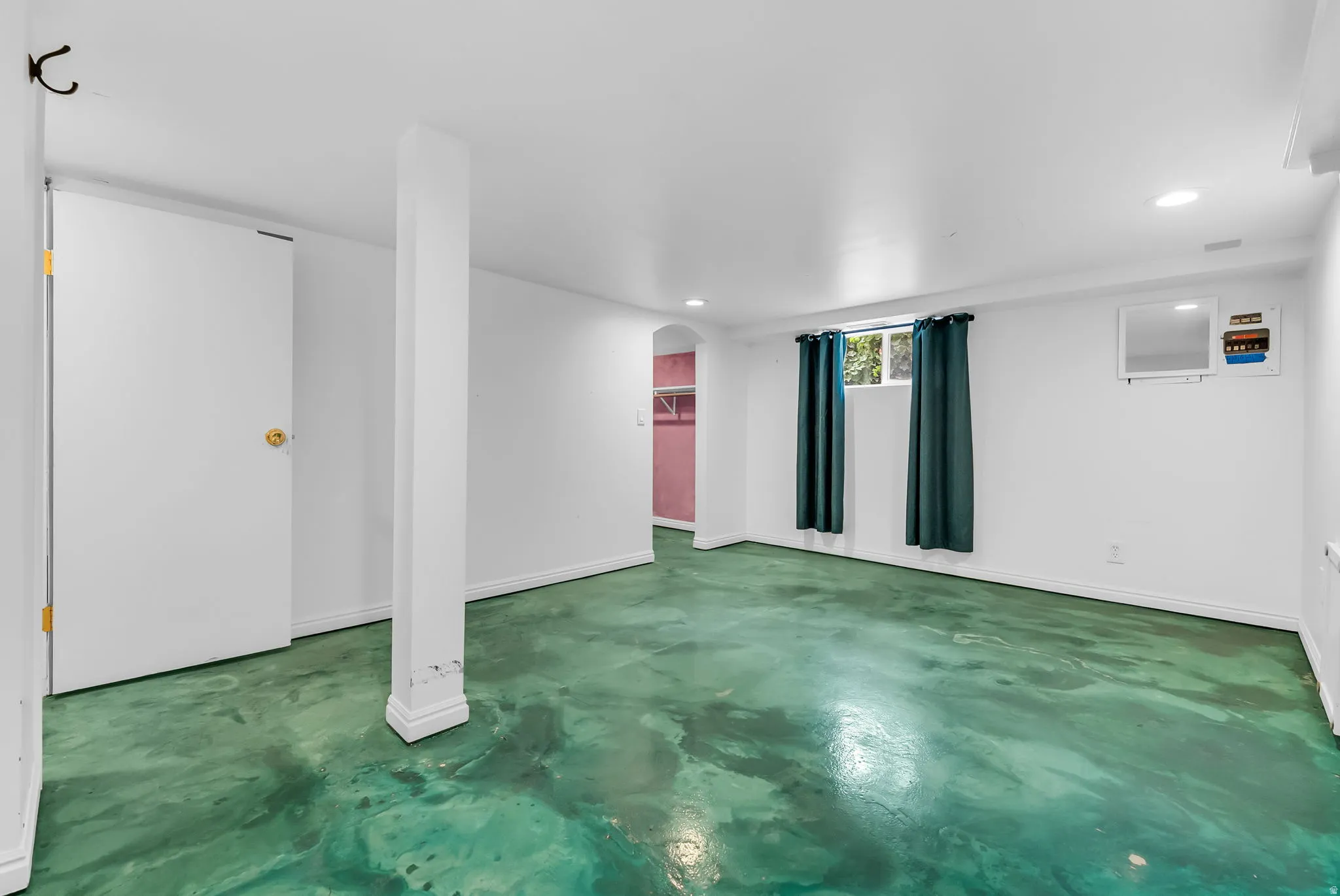 Spacious room featuring unique green-toned flooring, white walls, and recessed lighting