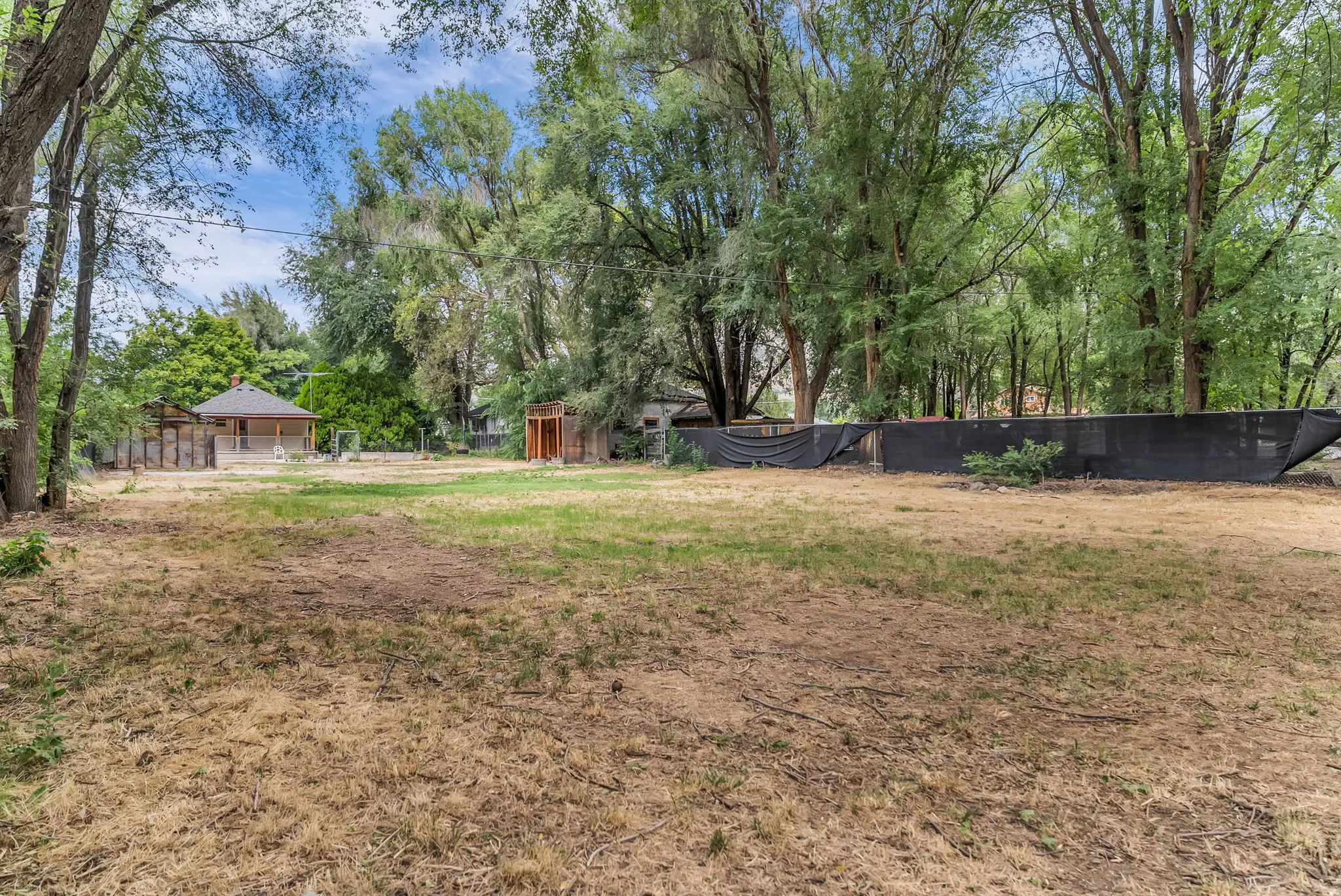 Expansive outdoor space featuring mature trees and a detached structure with a hip roof