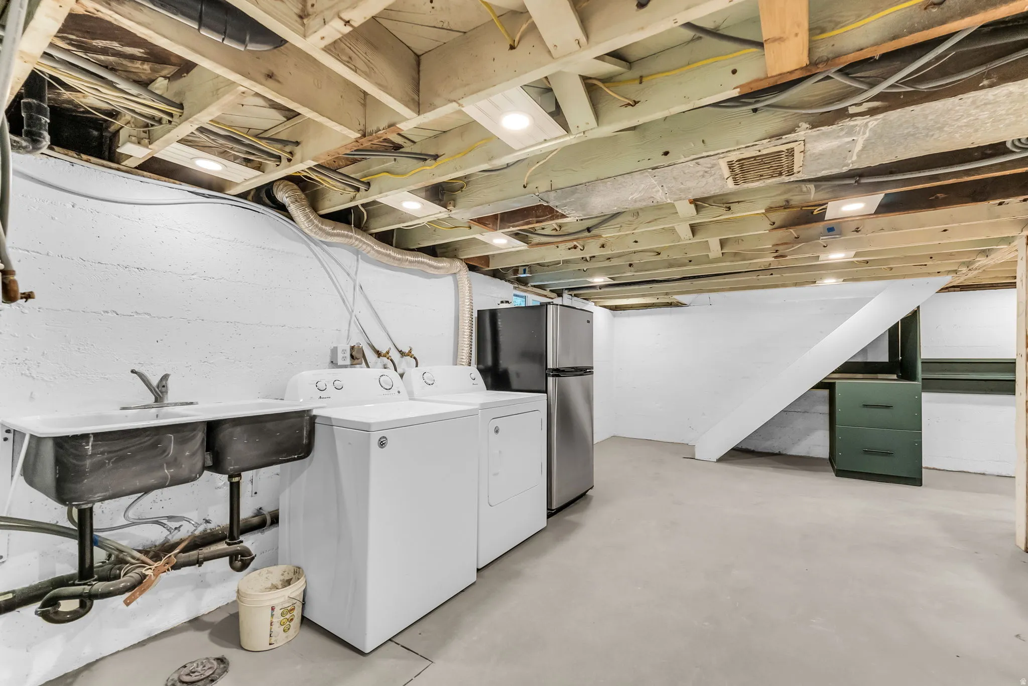 Basement utility space featuring a double basin sink, exposed ceiling joists, recessed lighting, and a painted concrete floor