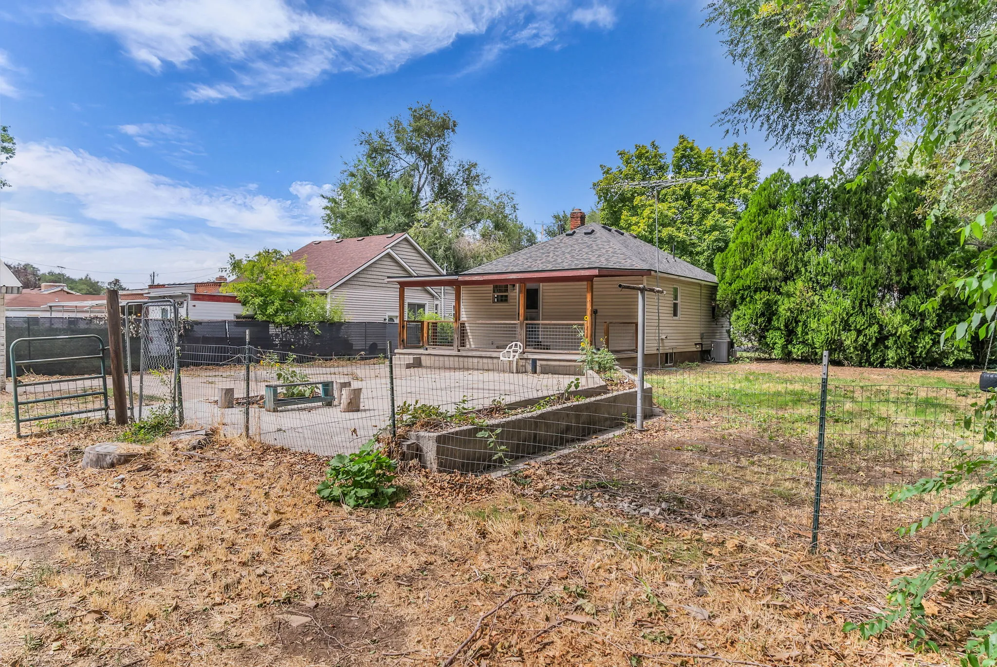 Expansive backyard featuring a concrete patio, covered porch, and partial fencing