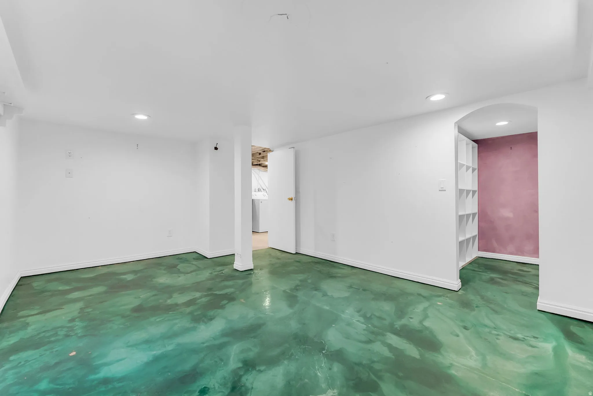 Recessed lighting, painted concrete flooring, arched doorway, and built-in shelving