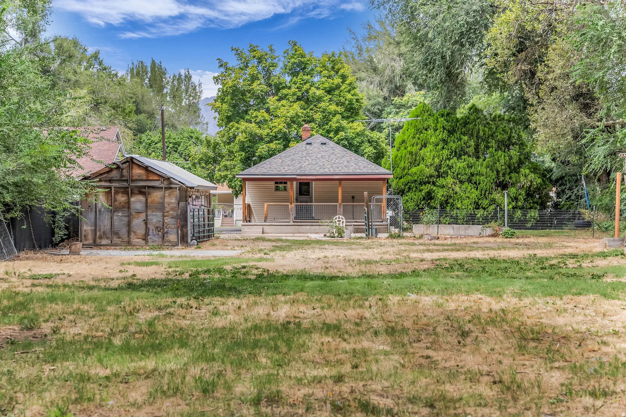 Charming rural residence featuring a brick exterior and covered front porch, situated on expansive grounds with mature landscaping and established trees throughout the property