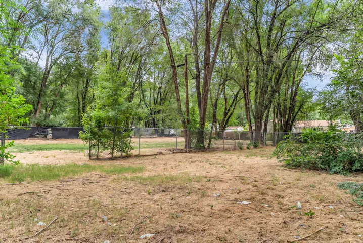 Expansive lot featuring mature trees and chain-link fencing